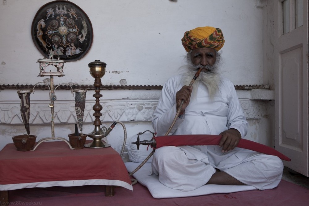 Старик курит кальян на гашише в Индии.